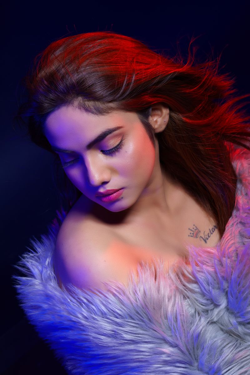 Vibrant studio portrait of a woman with colorful lighting and stylish fashion.
