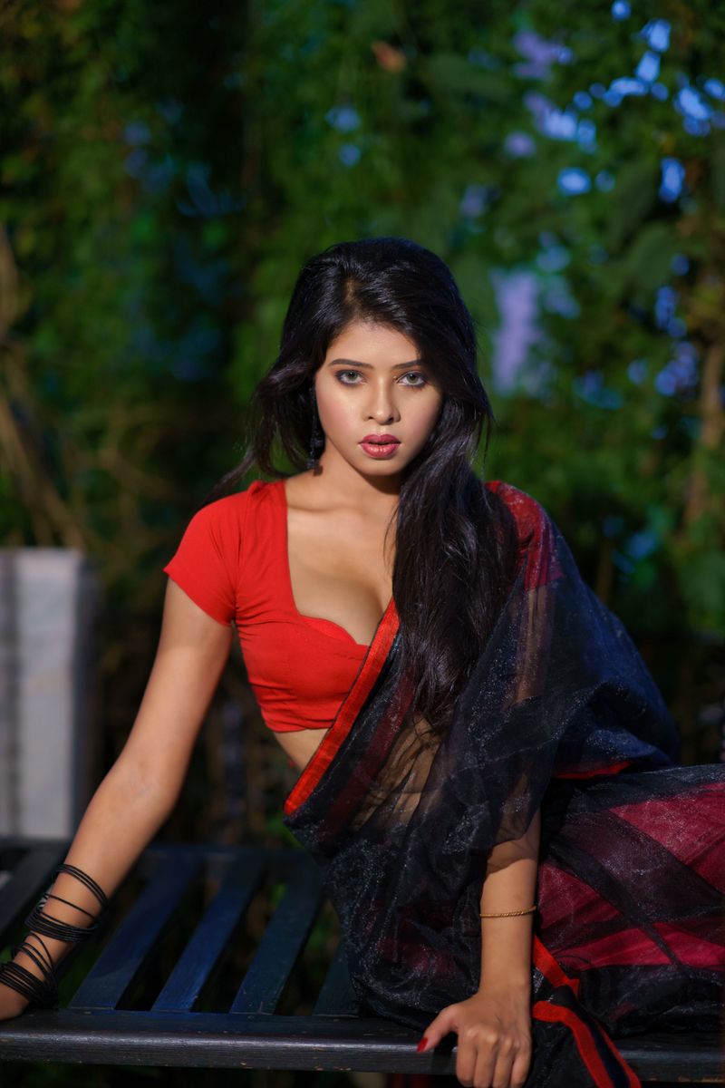 Beautiful woman in a red sari posing outdoors, highlighting elegance and cultural fashion.