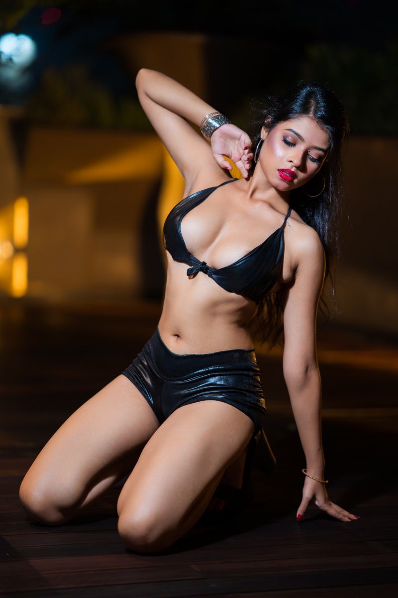 Stylish woman in black swimwear posing at night, exuding elegance and confidence outdoors.