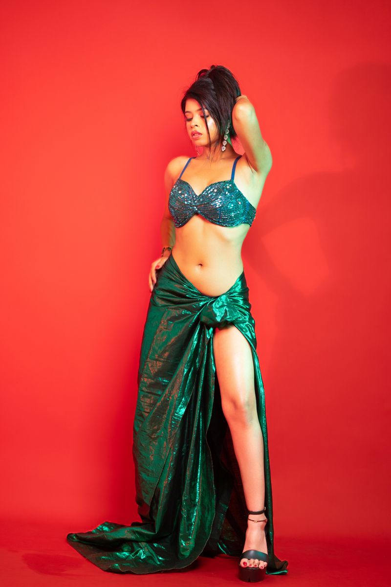 Stunning studio portrait of a woman in elegant fashion attire on red backdrop.