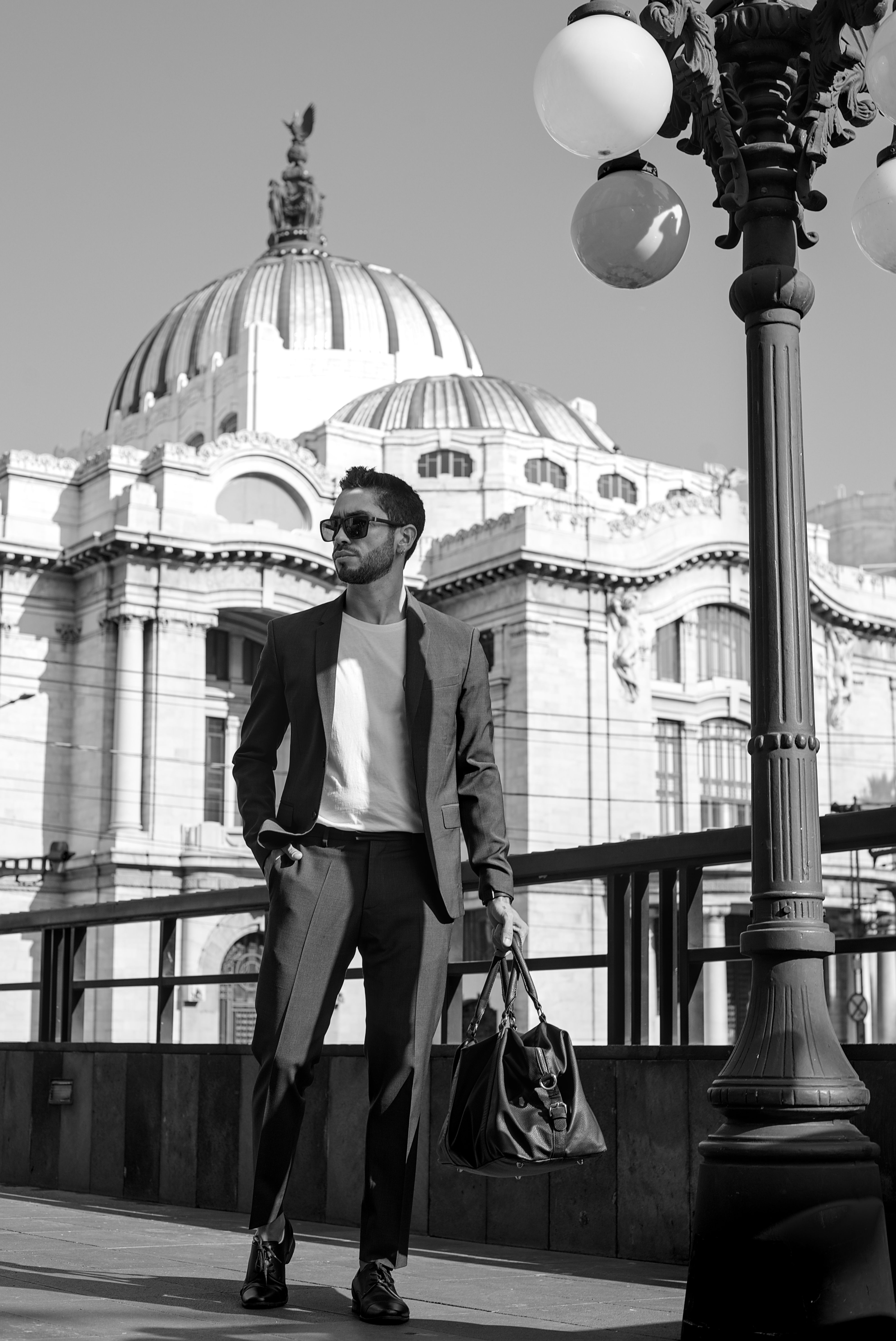 Man in suit walks near iconic architecture, exuding elegance and style.