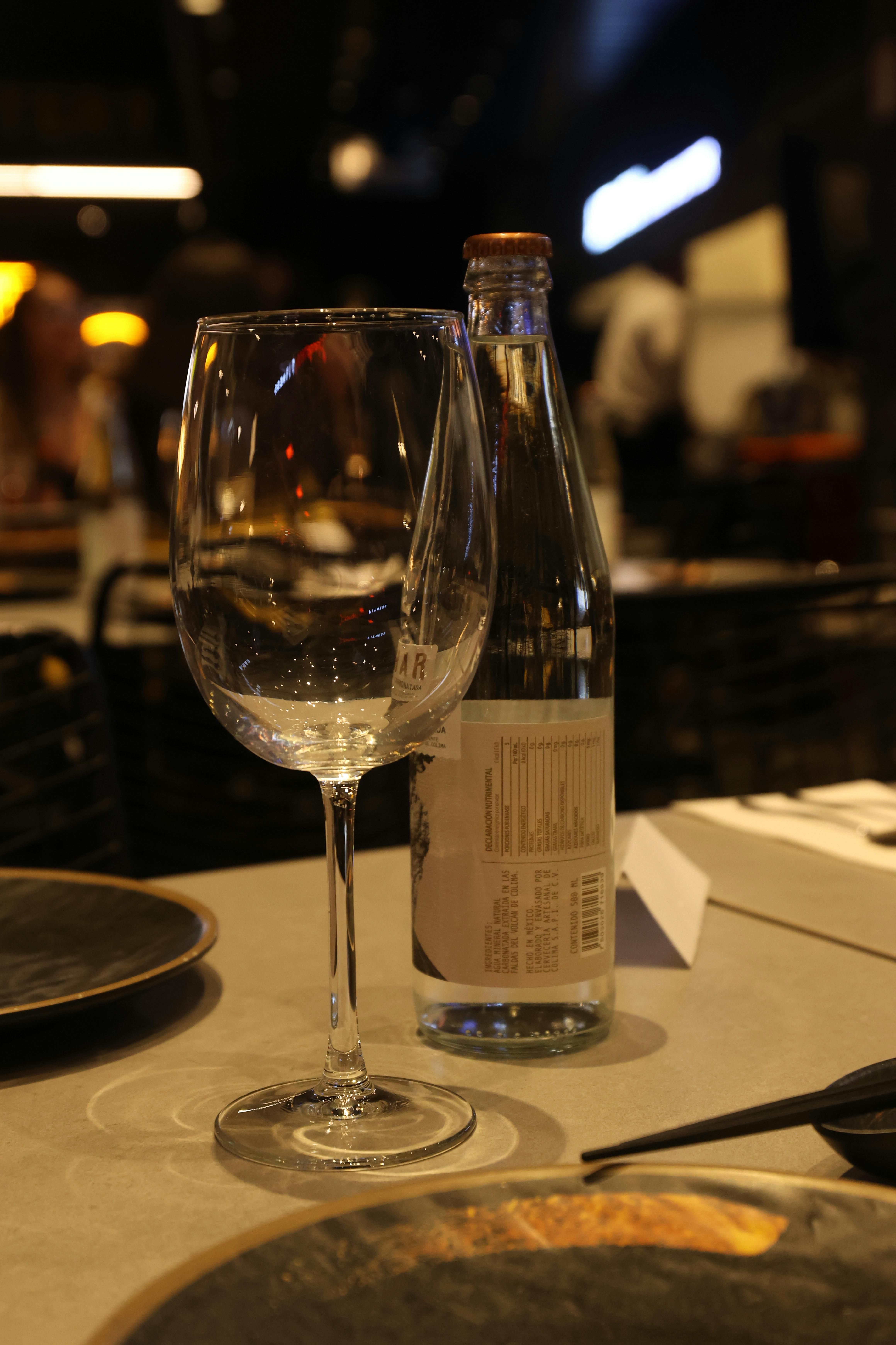 a wine glass and bottle sit on a table