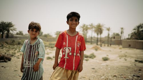 Free Two young boys enjoying a sunny day outdoors in Iranshahr, Iran with palm trees in the background. Stock Photo