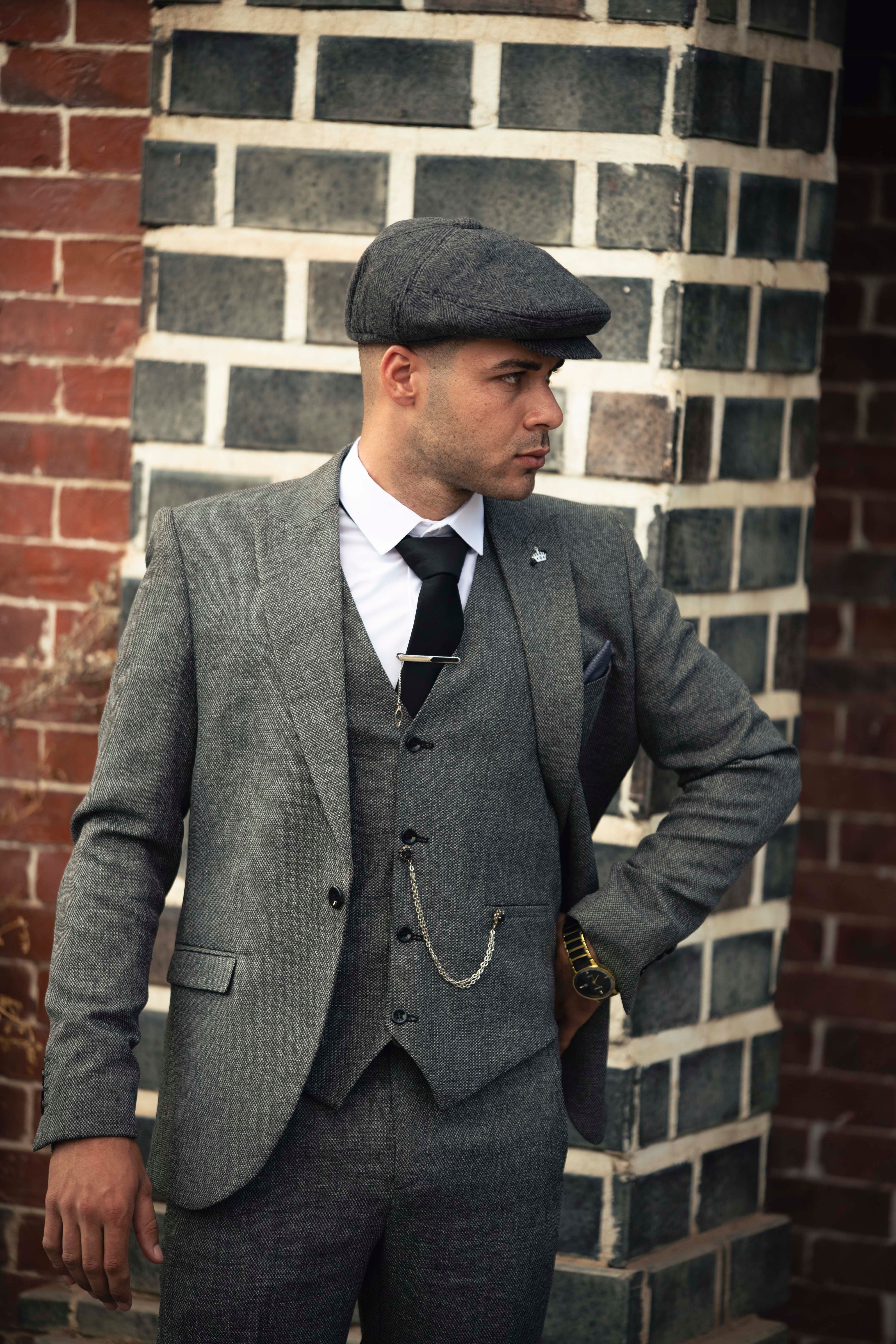 A man in a suit and hat is leaning against a brick wall · Free Stock Photo