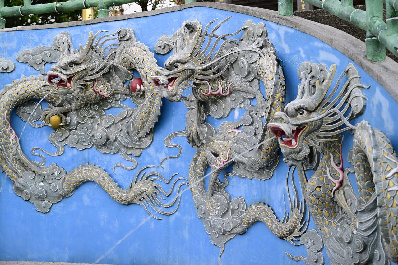 detailed stone dragon sculpture on an ornate blue wall outdoor setting