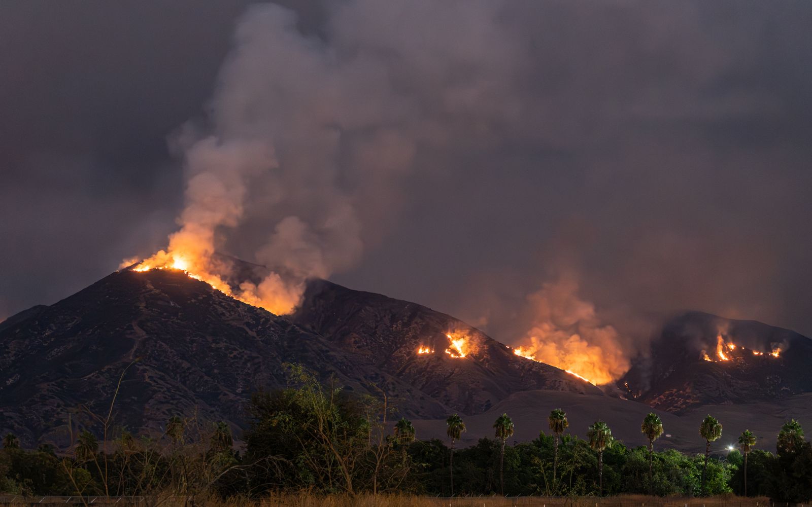A wildfire burning across hills at night in Redlands, California