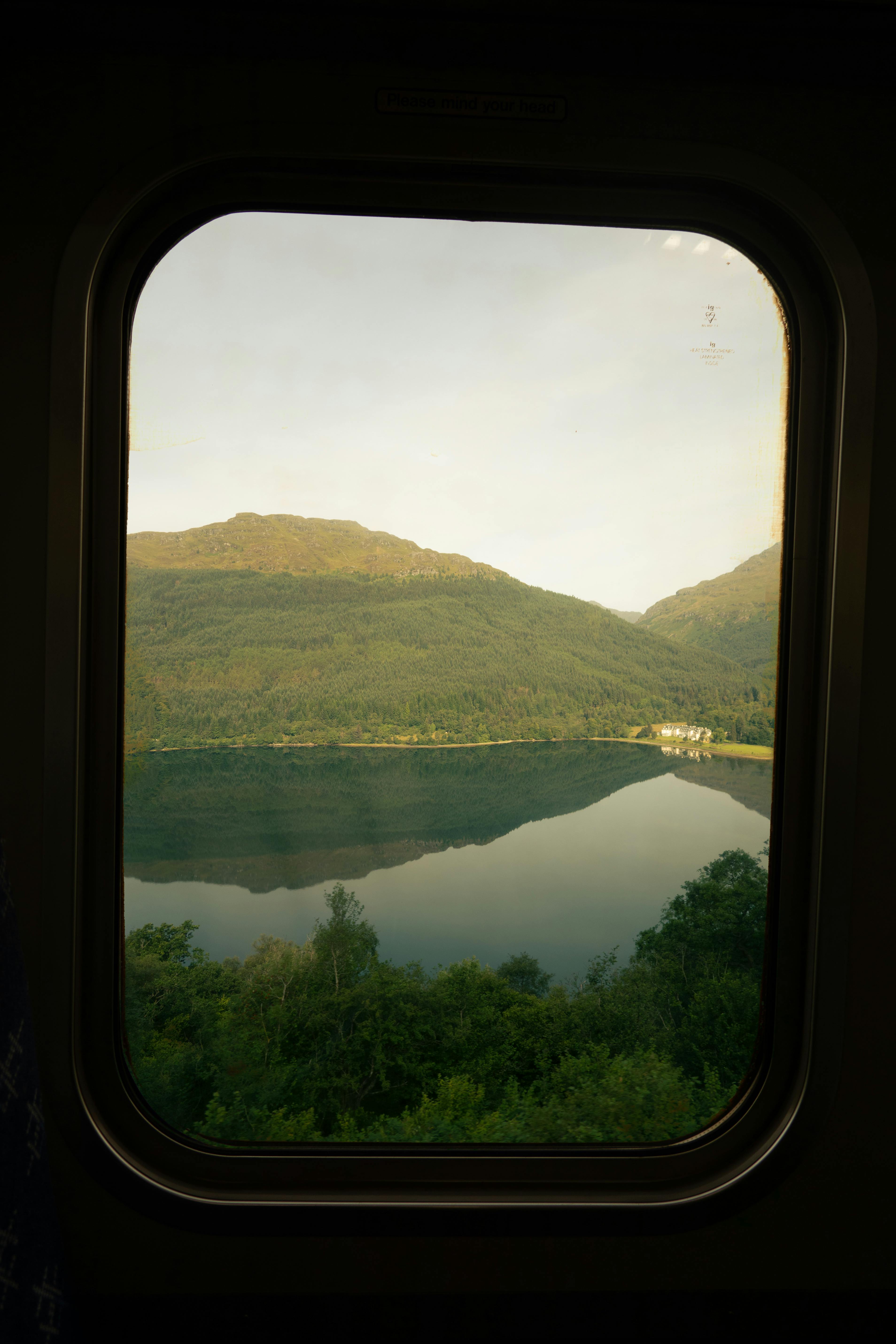 A beautiful view of a serene mountain lake from a train window, capturing nature's reflection.