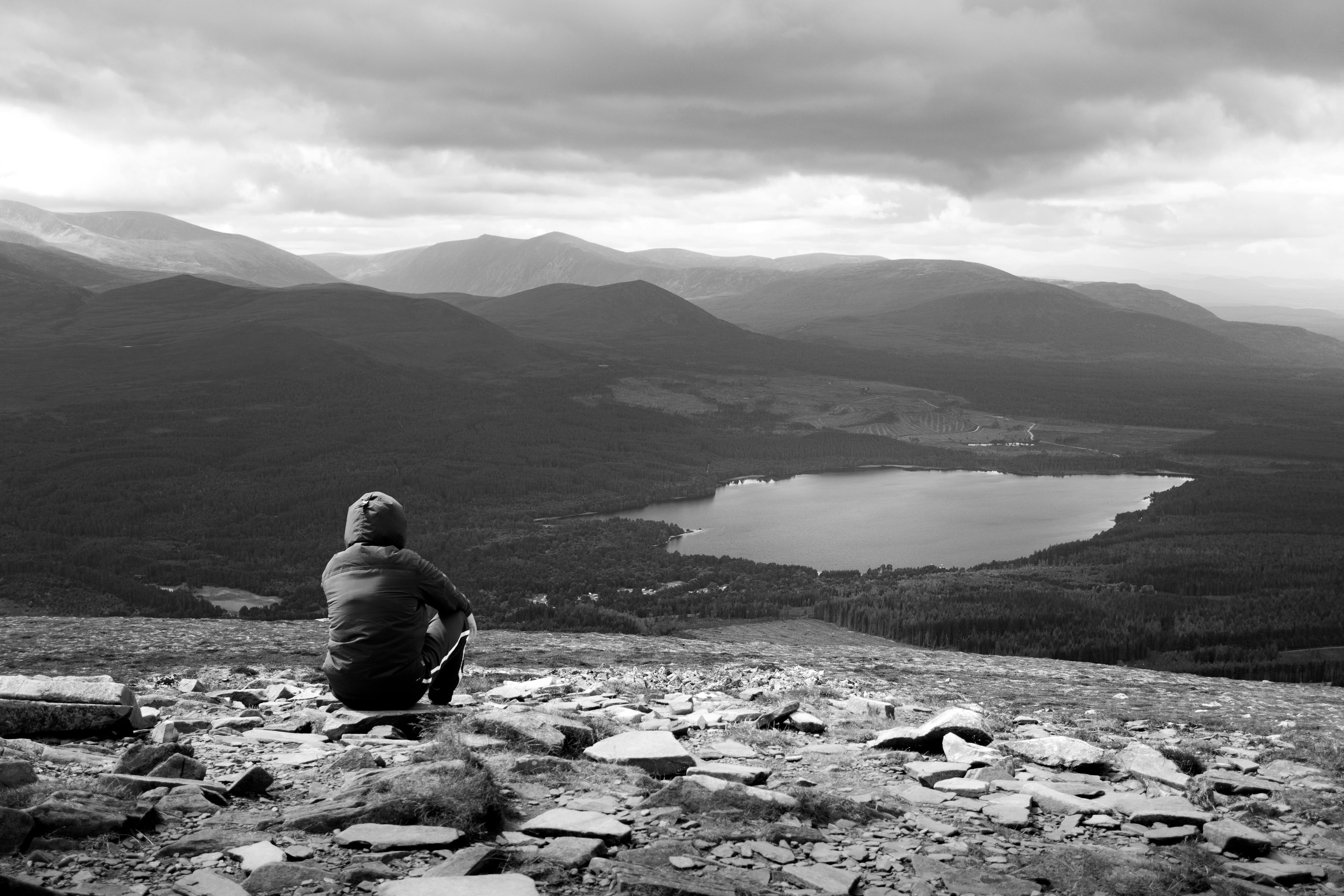 Person enjoys solitude overlooking mountain lake, surrounded by stunning landscape.