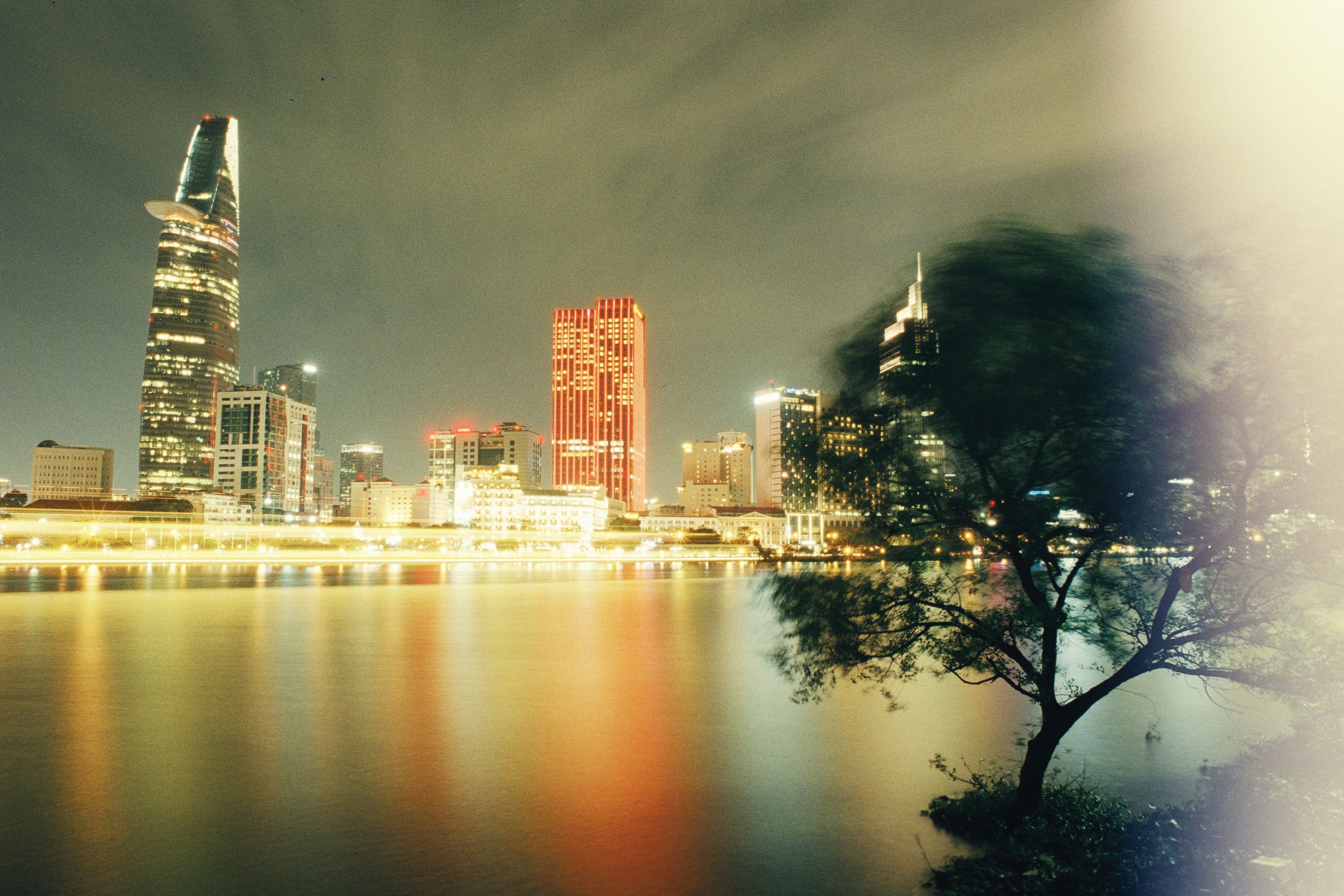 Ho Chi Minh City skyline at night, skyscrapers lit up and reflected in the Saigon river