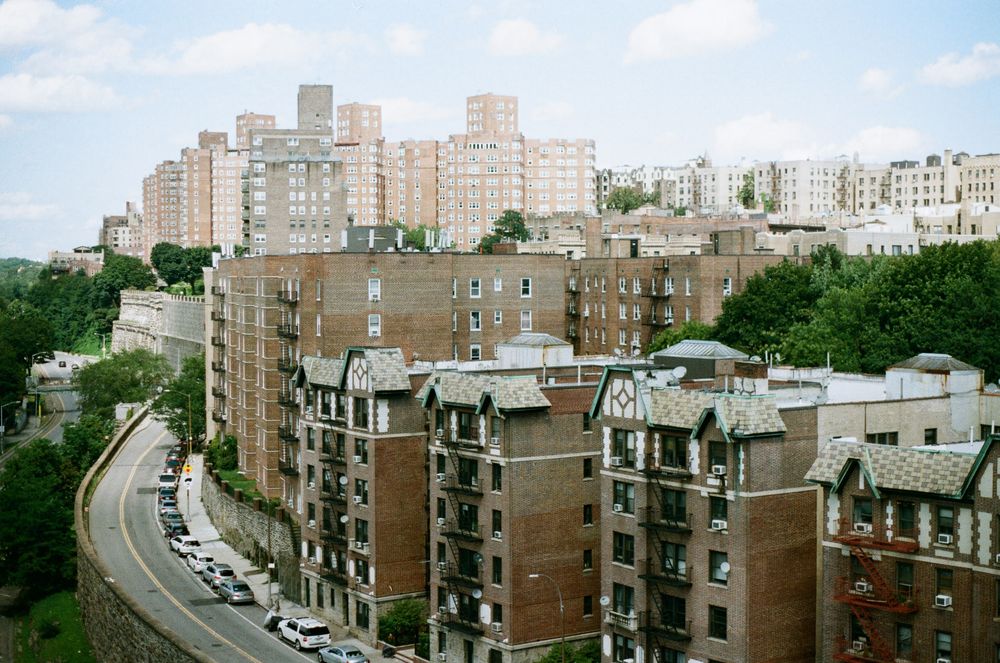 Prewar apartment buildings on a Bronx residential block in summer.