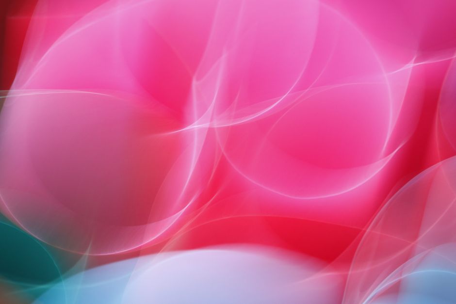 Dynamic abstract light pattern with vibrant pink and red hues, capturing movement and energy.