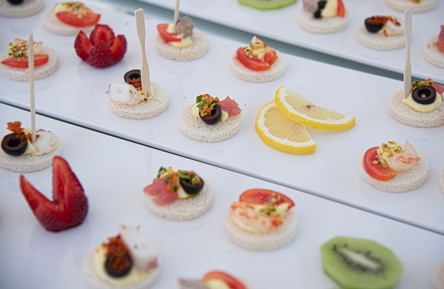Close-up of assorted appetizers with fruits and vegetables on a white plate.