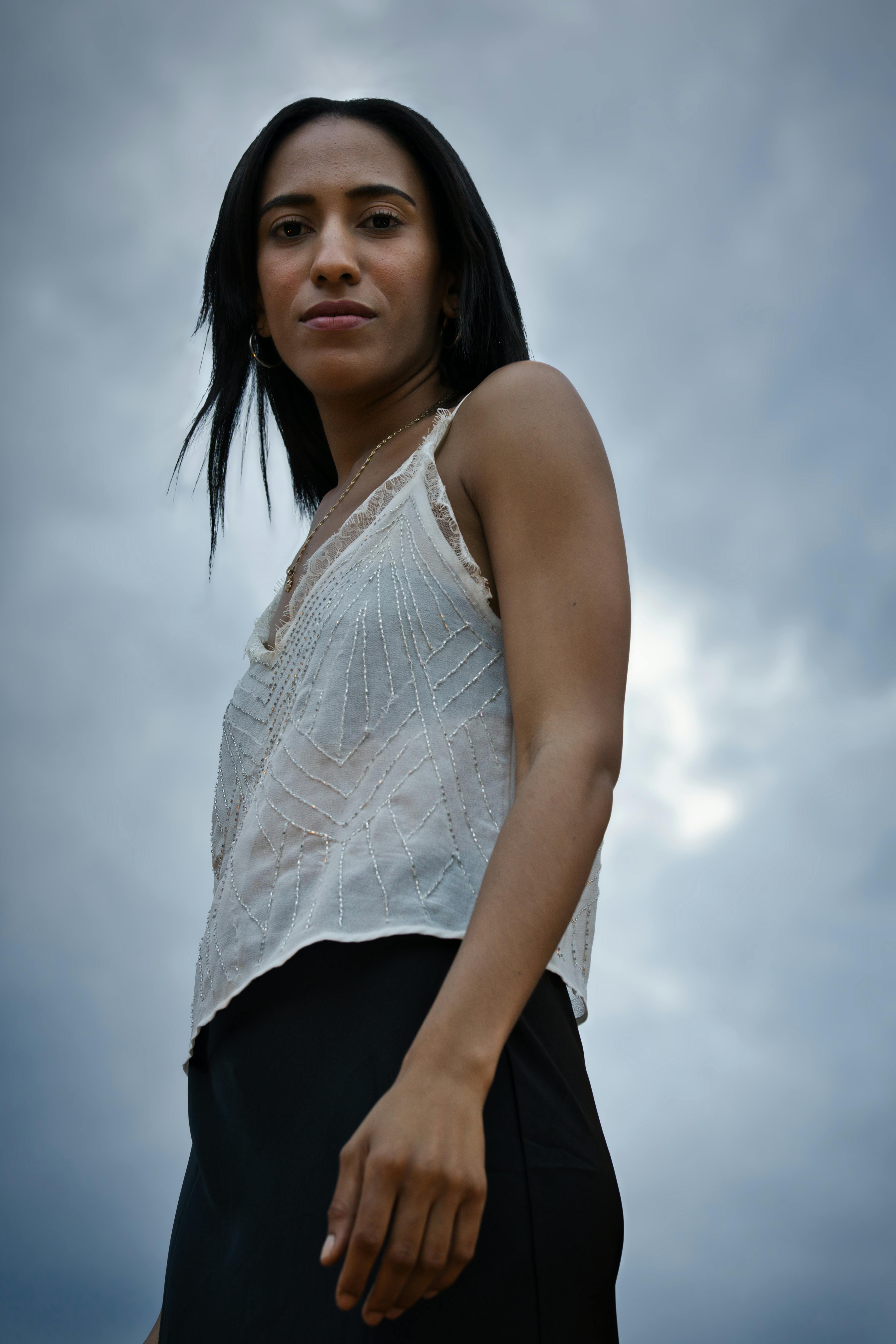Elegant outdoor portrait of a woman posing confidently against a cloudy sky in Berlin.