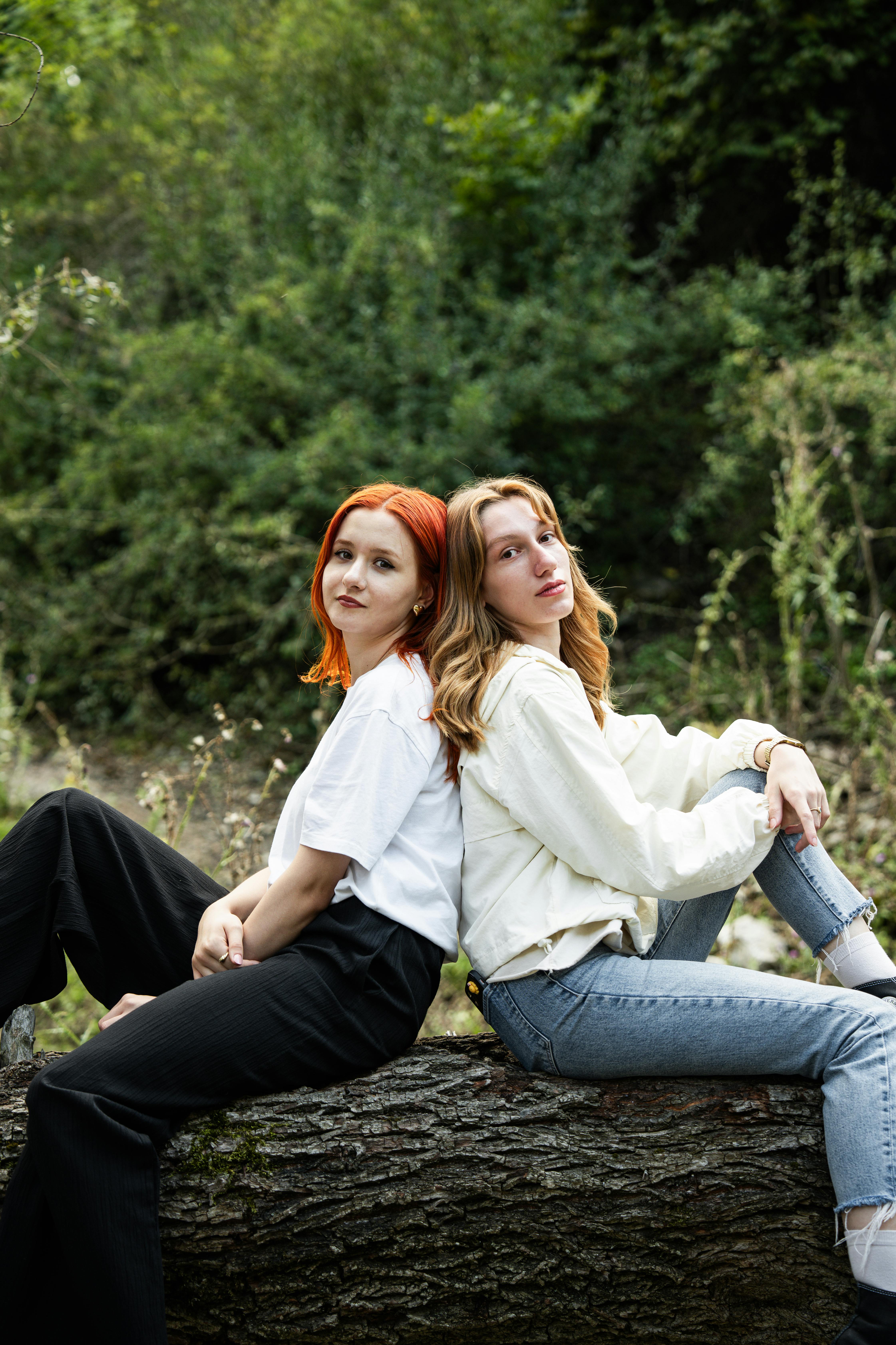 two girls sitting on a log in the woods