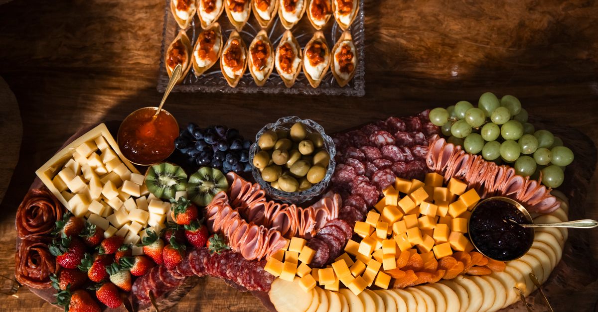 Uma luxuosa tábua de frios com queijos, frutas, carnes e azeitonas. Perfeita para festas ou encontros gourmet.