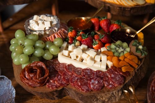 Free Savory charcuterie board with cheeses, fruits, and meats on a rustic wooden table. Stock Photo