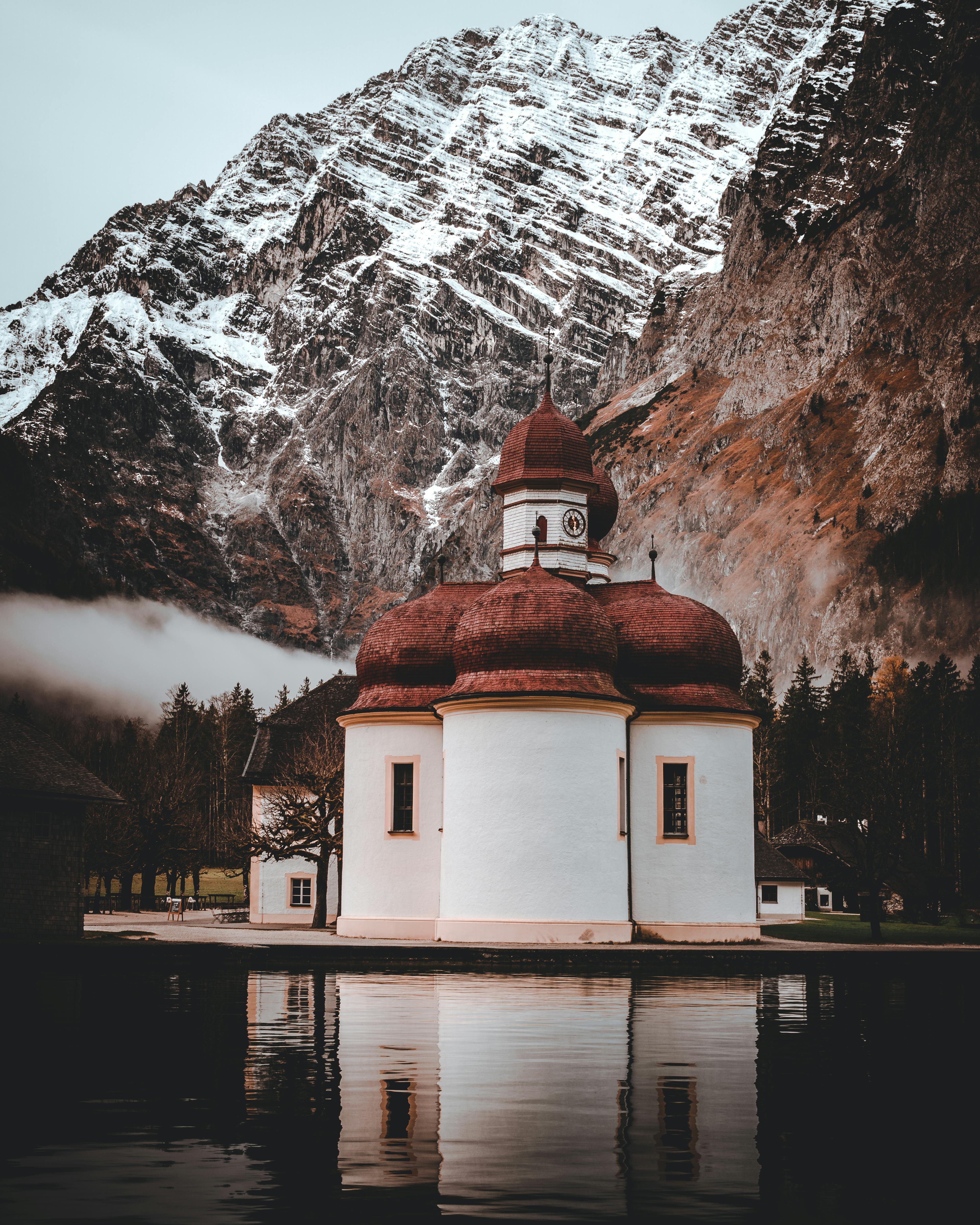 白雪皑皑的山峰下，一个平静的山湖依偎在迷人的小教堂旁