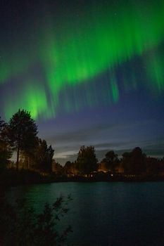 Capture the breathtaking Northern Lights over a tranquil lake in Kiruna, Sweden's night sky.