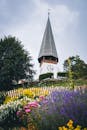 色彩缤纷的夏季花园环绕着风景如画的教堂塔楼，营造出宁静的乡村景观