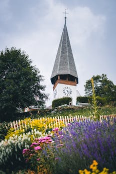 色彩缤纷的夏季花园环绕着风景如画的教堂塔楼，营造出宁静的乡村景观