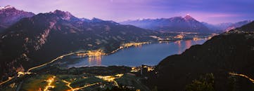 黄昏时分，一个宁静的高山湖泊在雄伟的山峦背景下，呈现出令人叹为观止的全景和充满活力的倒影