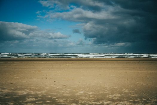 A peaceful Nordic beach under dramatic storm clouds with ocean waves and sandy shore.