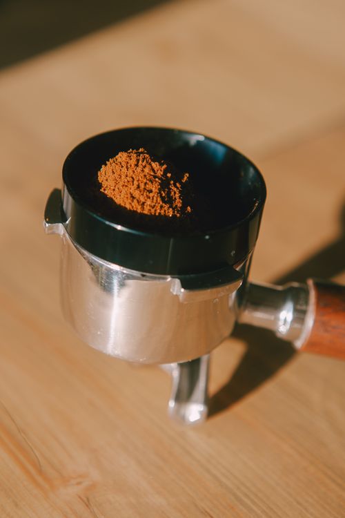 Free Focused shot of a portafilter holding ground coffee, highlighting coffee preparation. Stock Photo