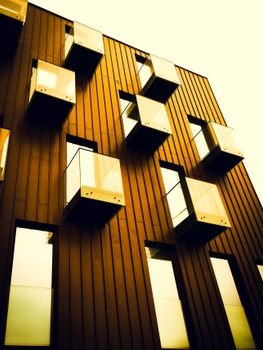 Contemporary building facade with geometric balconies and reflective windows under a warm sunset glow.