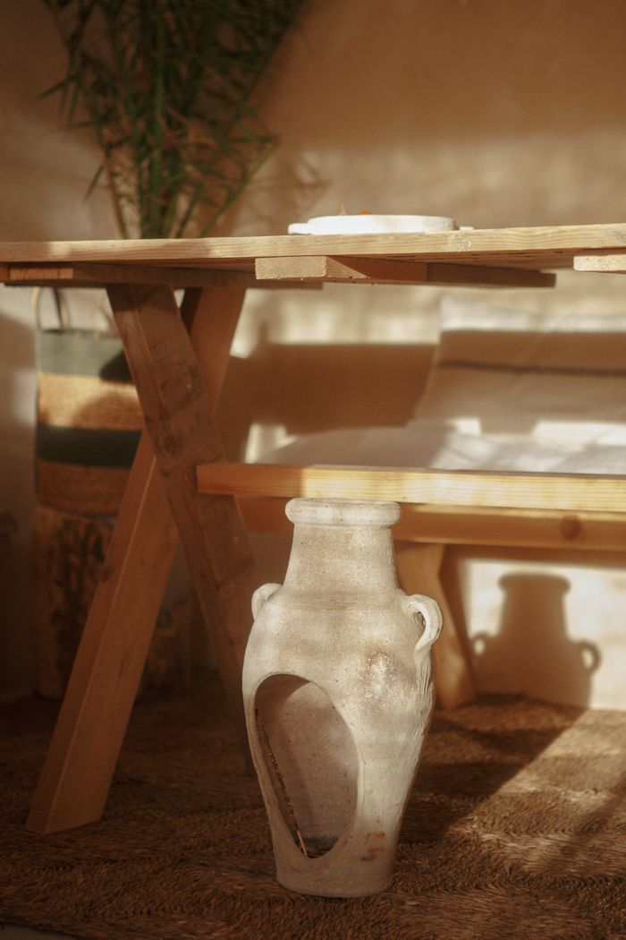 Rustic wooden table and clay vessel in a warm plaster room, by Raymond Petrik on Pexels