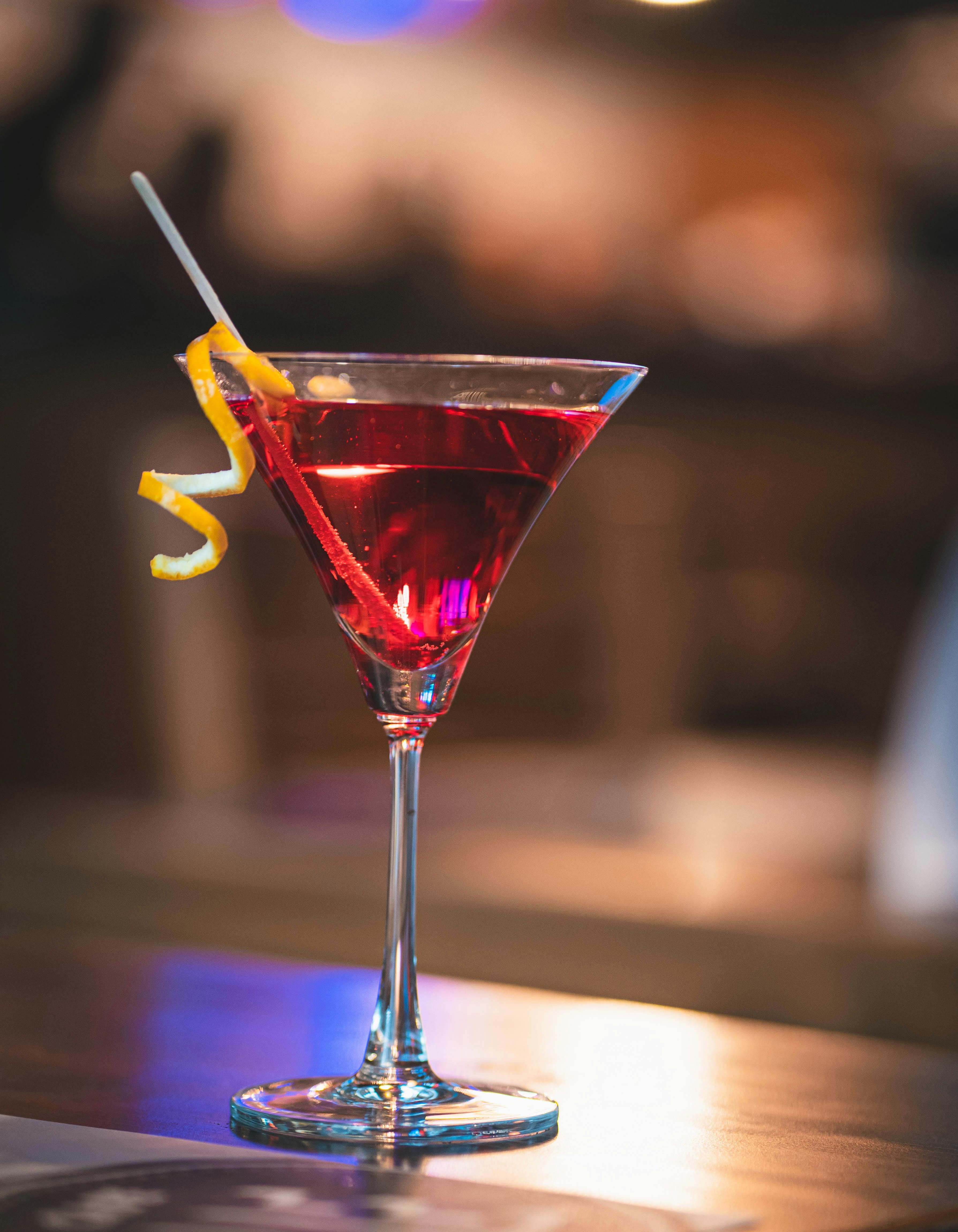 cocktail topped with lime slice single glass of dry martini in a restaurant over a wooden table