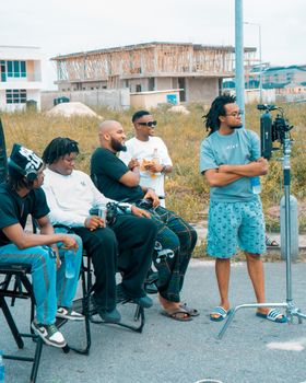 Group of men casually filming with equipment outside under construction area.