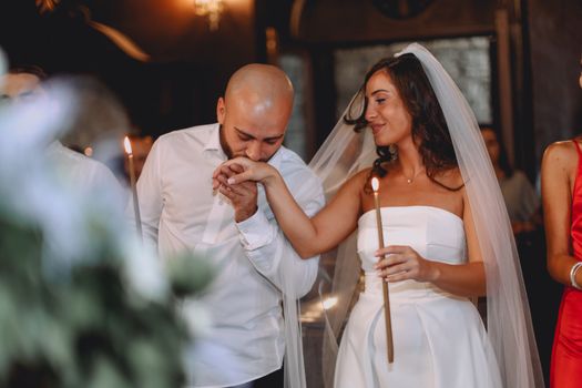 Bride and groom share an intimate moment during a candlelit wedding ceremony indoors.