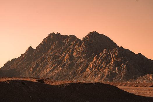 Dramatic sunset view of rugged mountains in Sharm El-Sheikh, Egypt, with warm hues.