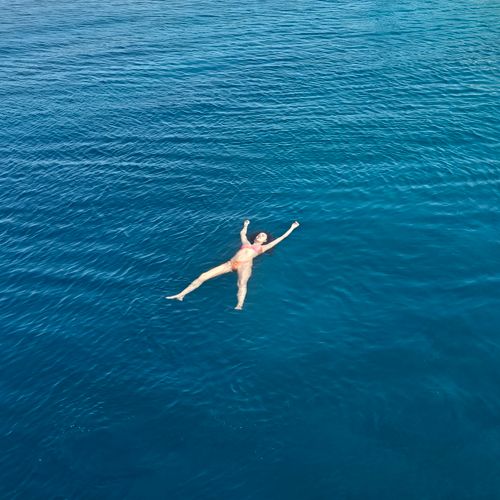 Free Aerial view of a woman floating in the ocean, enjoying a tranquil vacation moment. Stock Photo