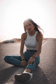 阳光明媚的道路上，一位时尚女性休闲地坐着，肖像充满时尚感