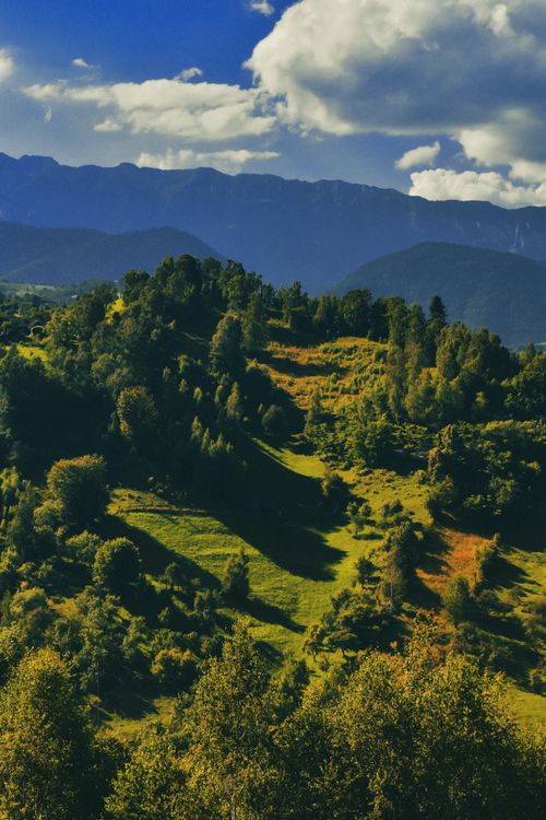 Free Stunning aerial view of a lush green mountainous landscape under a partly cloudy sky. Stock Photo