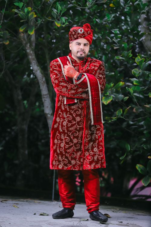 Free Portrait of a Bengali groom in ornate red traditional attire outdoors. Stock Photo