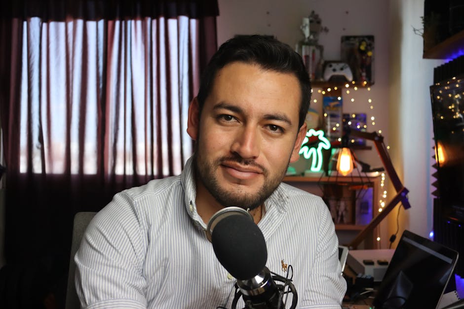 Descript vs CapCut: Auto Captions for Podcasts (2026) Casual home podcast recording setup with a man using a microphone in a cozy, decorated space.