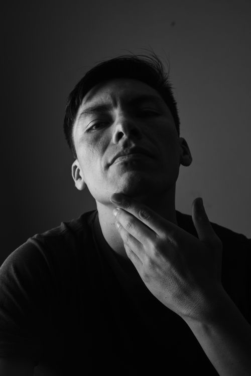 Free A moody black and white portrait of a man with deep shadows. Stock Photo
