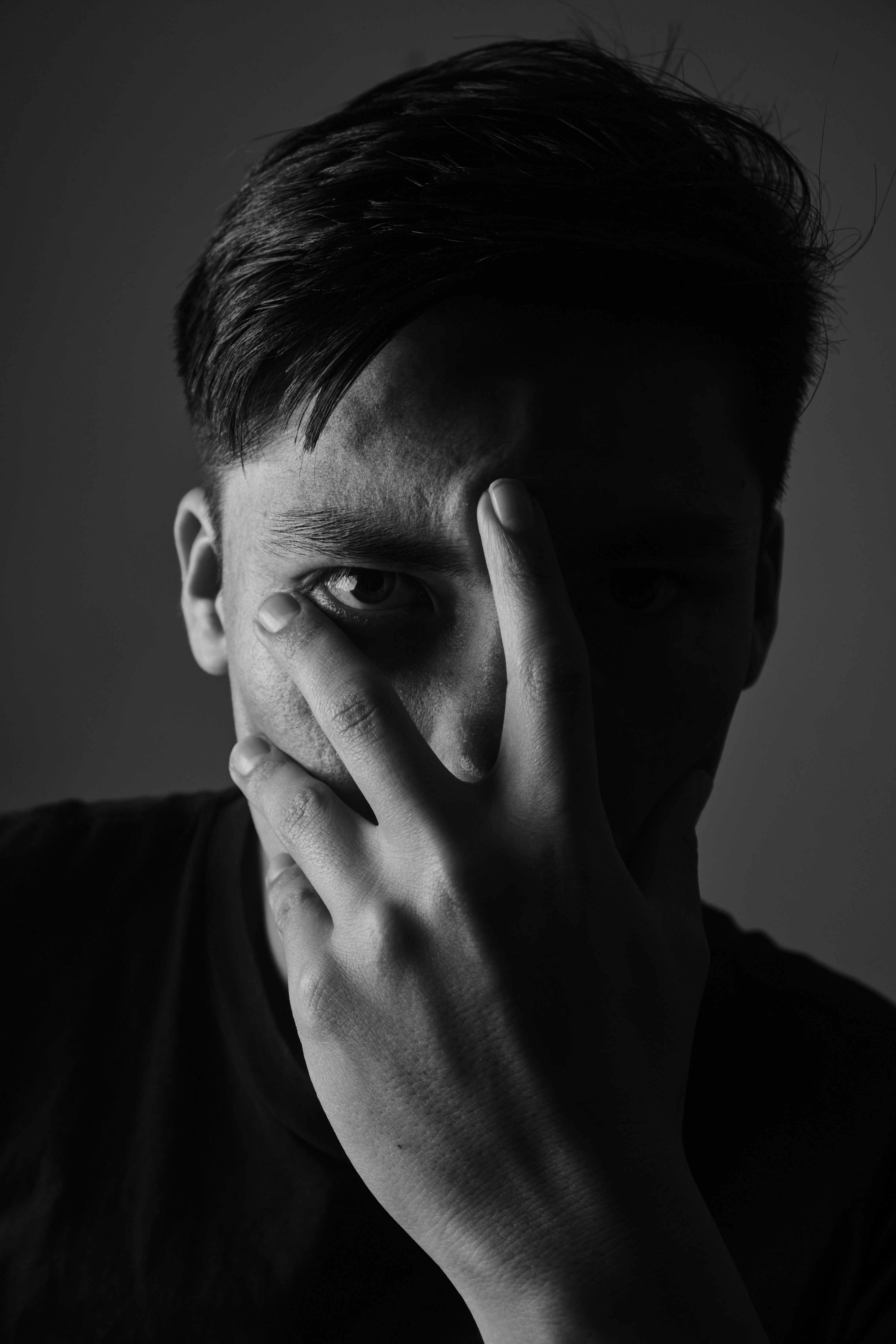 Artistic black and white portrait of a man with a contemplative expression, shot in a studio.