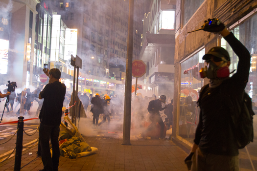 城市夜晚的街头抗议现场，烟雾弥漫，人群涌动