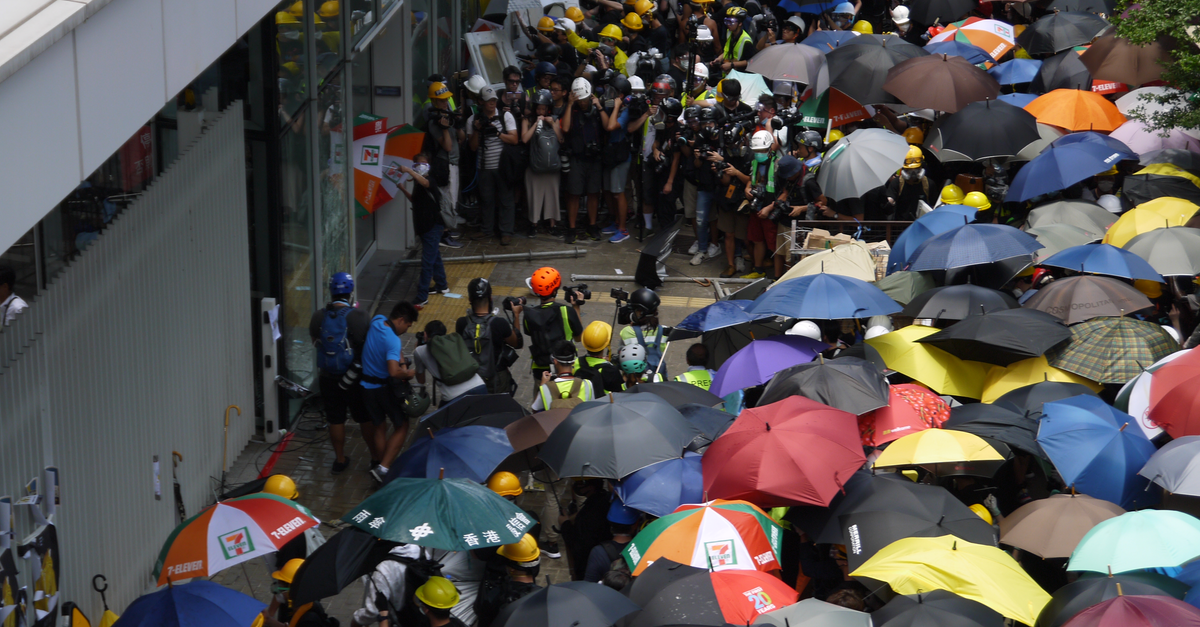 Crowded square with group of protestants near facade of building in rainy weather waiting in front of entrance