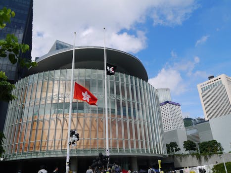 Contemporary Hong Kong architecture featuring flags, glass windows, and urban skyline.