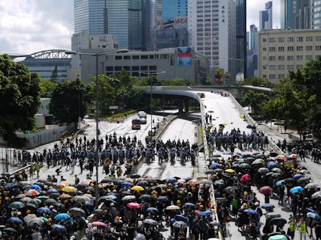 在多雨的城市街道上，一大群人撑着雨伞聚集在摩天大楼之间