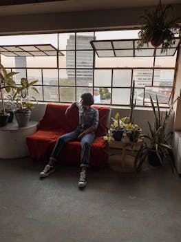 一位时尚女性随意地坐在绿植环绕的时尚室内空间里