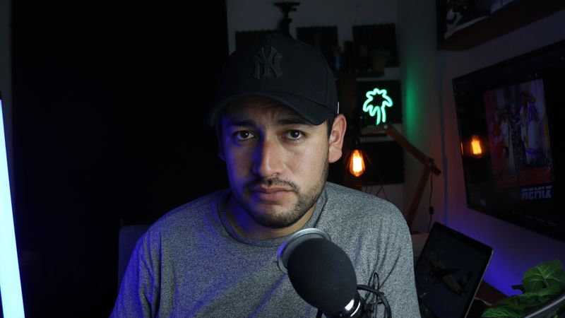 Male content creator in a home studio setup with microphone and soft lighting.