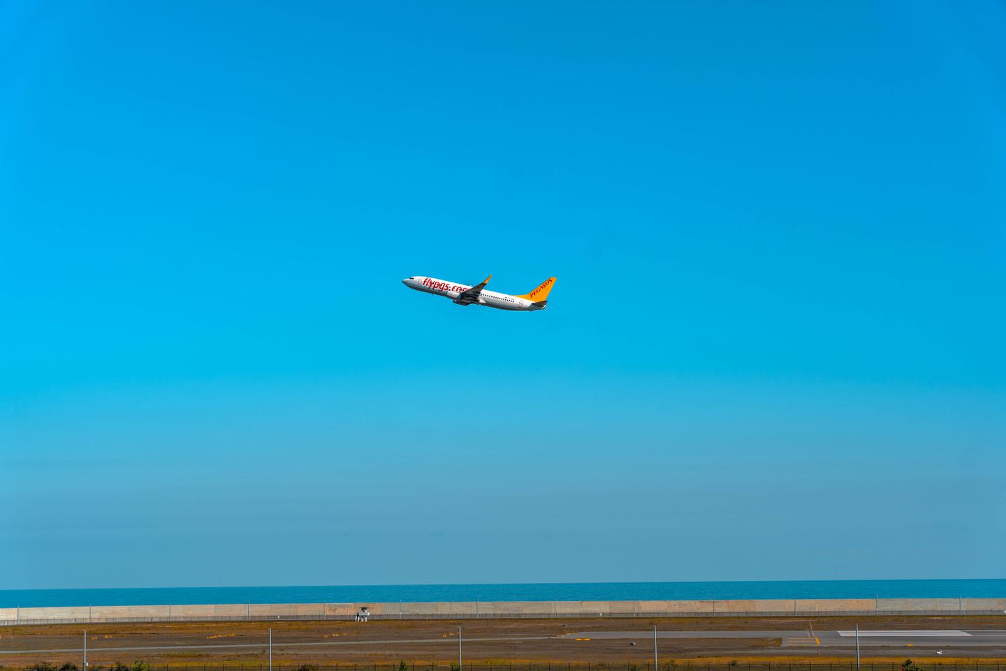 Commercial airplane taking off against bright blue sky over Long Beach Airport runway