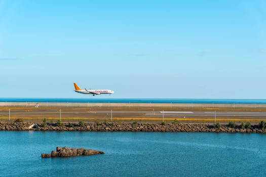 Commercial airplane approaches a seaside runway with clear blue skies in view.
