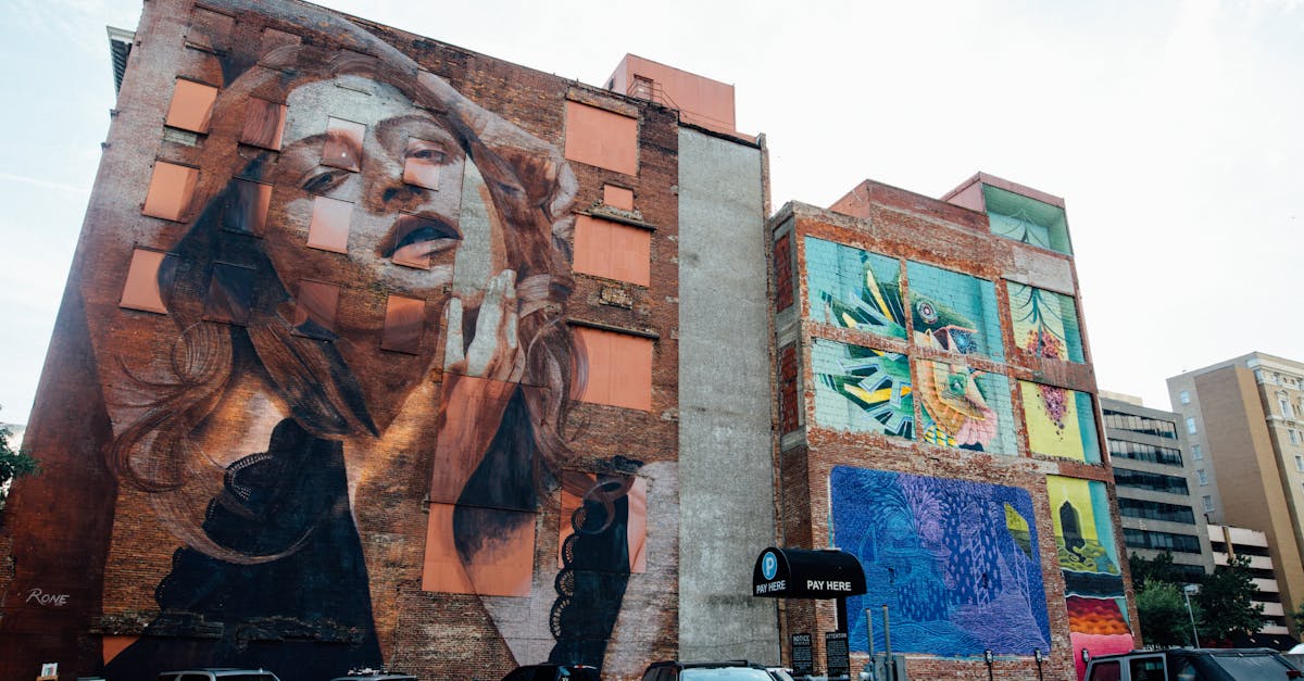 Dynamic street art murals on a city wall with parked cars below, showcasing urban creativity.
