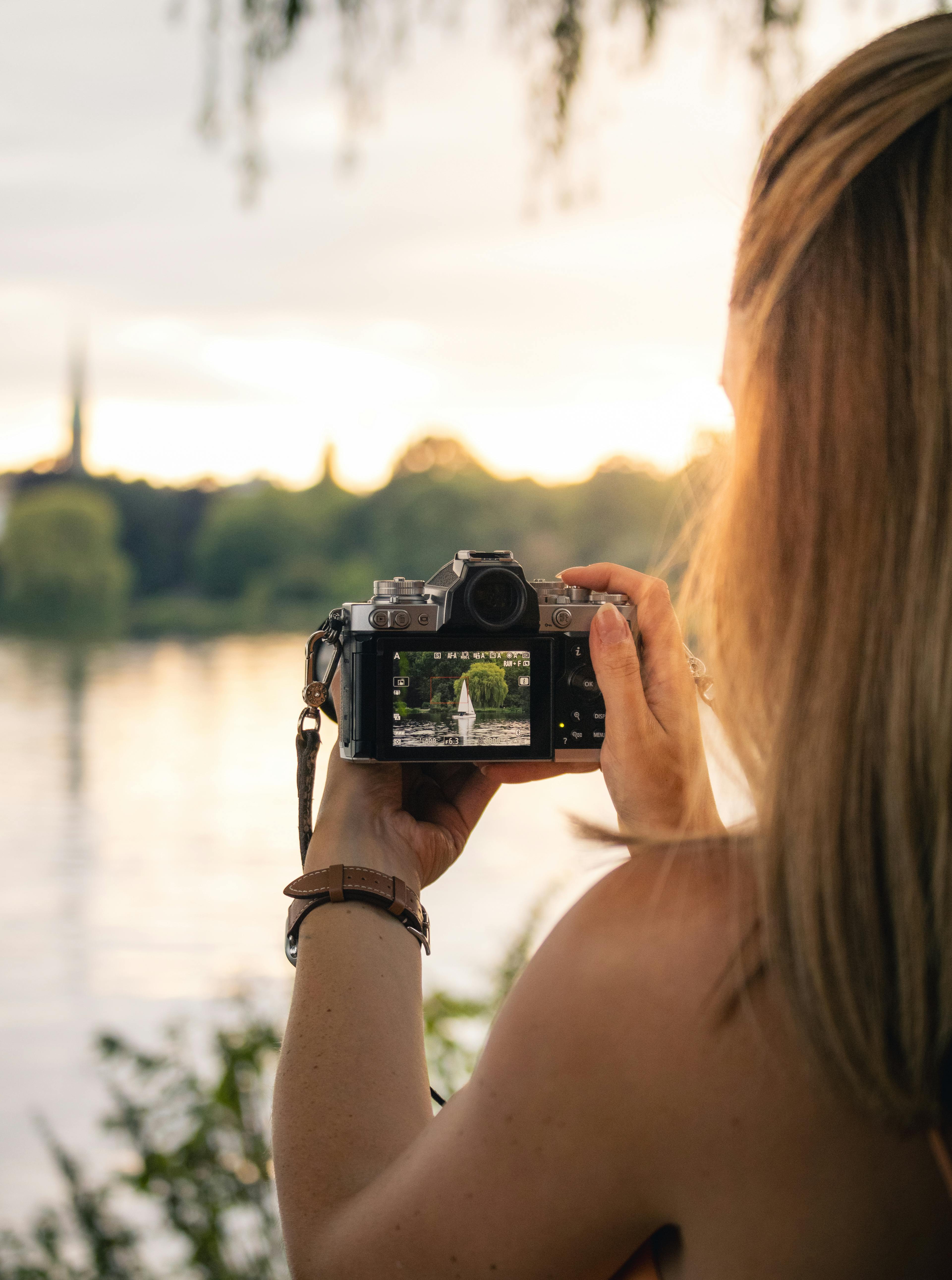 a woman taking a photo of a lake with her camera